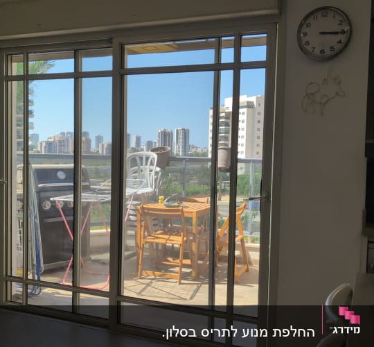 מרפסת עם שולחן וכיסאות דרך דלת זכוכית